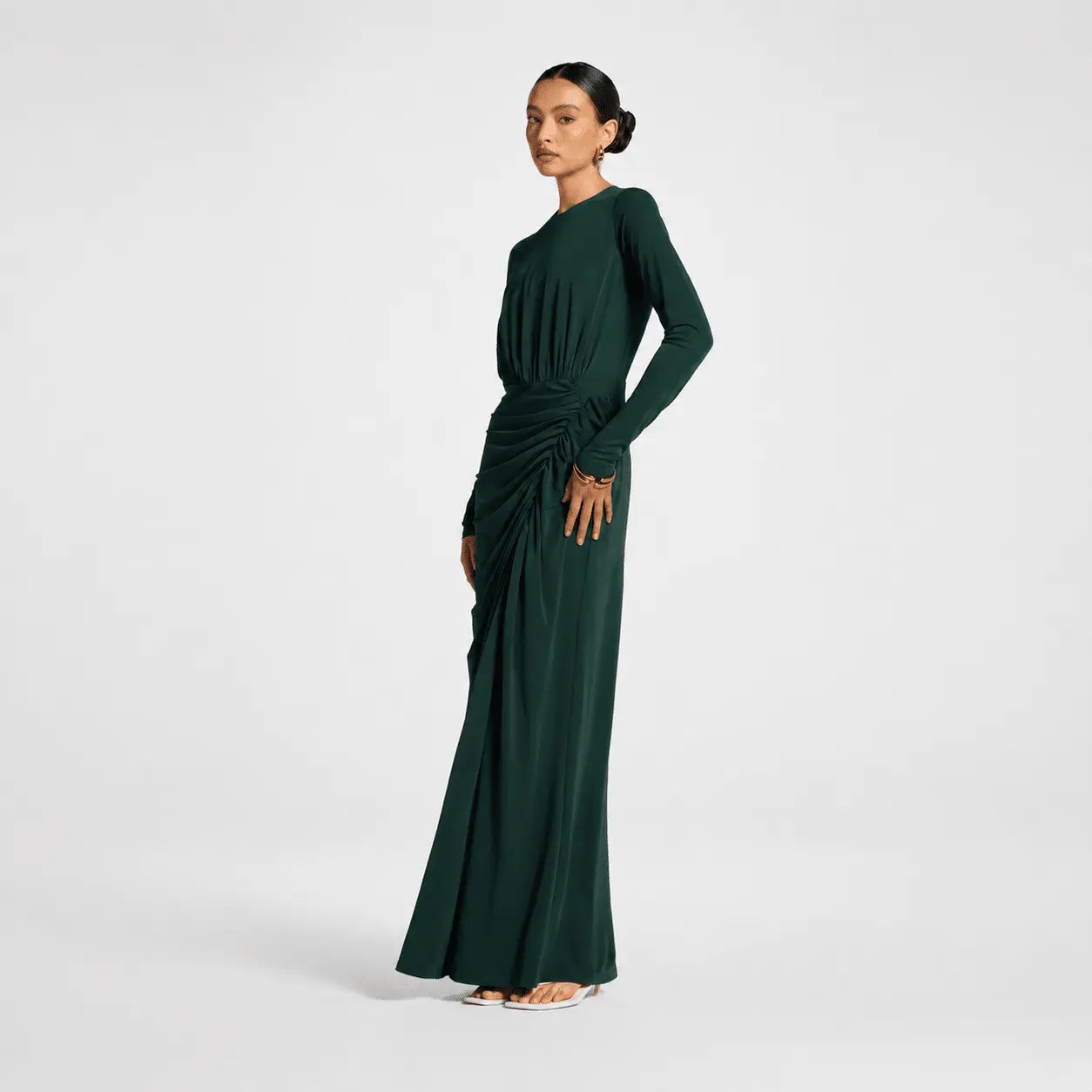 Woman wearing a dark green long-sleeve dress on a white background