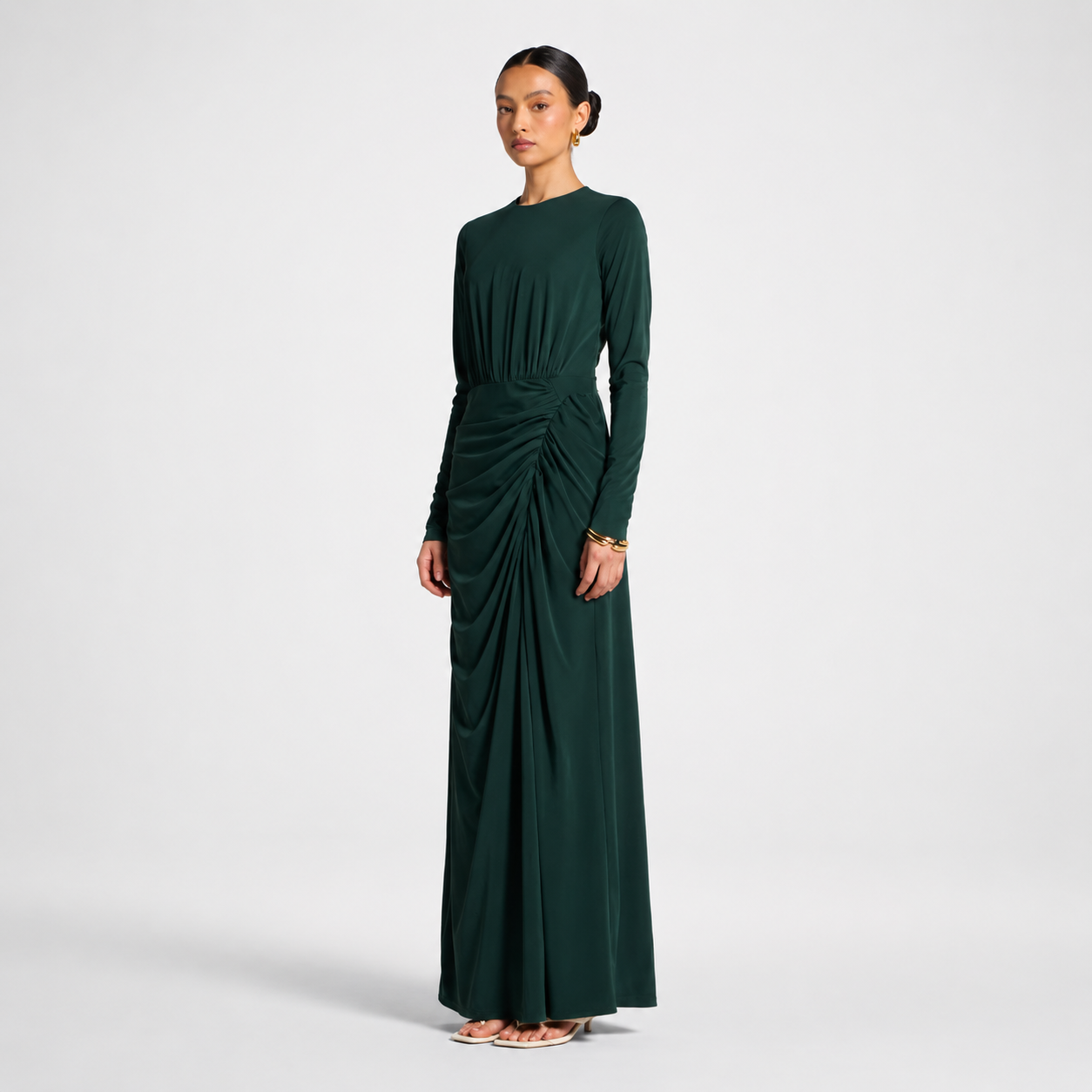 Woman wearing a dark green dress with a draped design on a light gray background