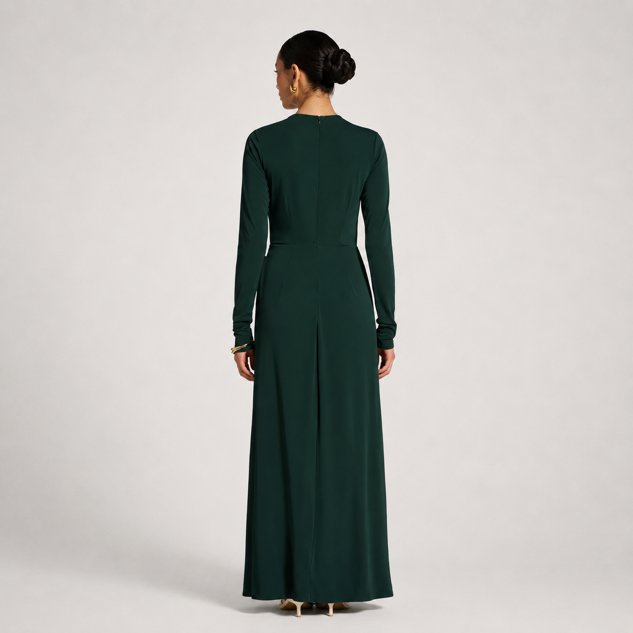 Woman wearing a long dark green dress on a light gray background