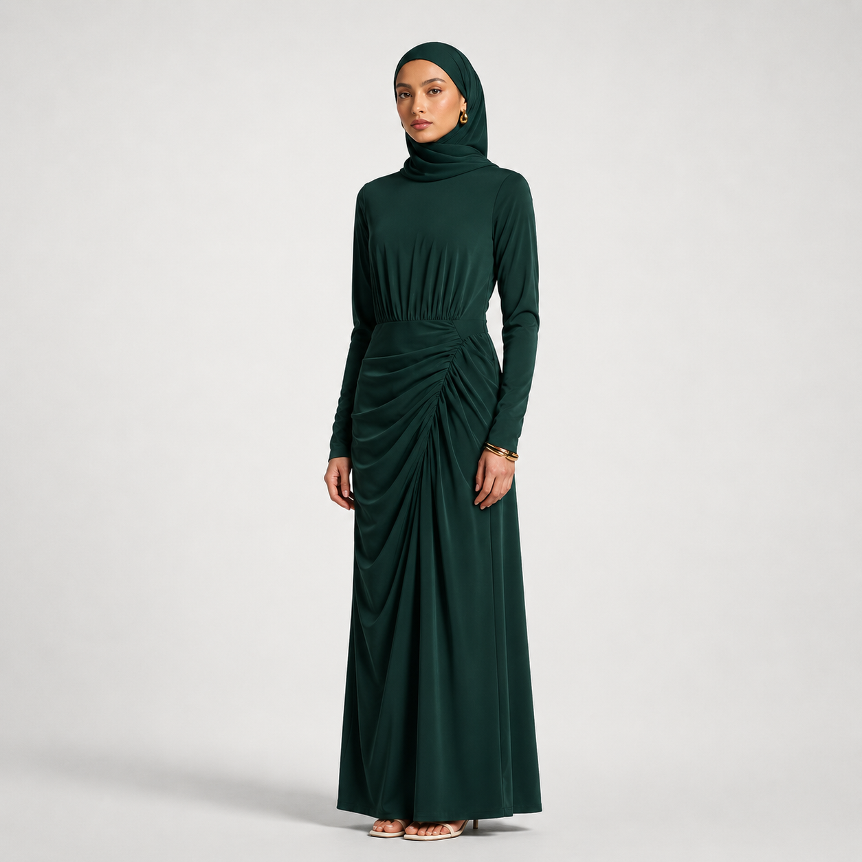 Woman wearing a dark green long-sleeve dress with a hood on a light gray background