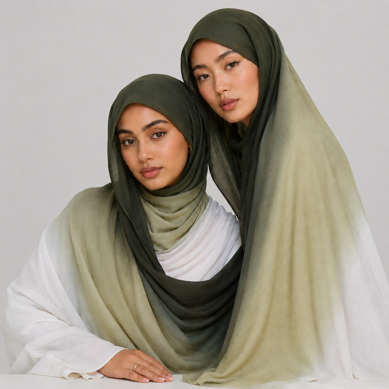 Two women wearing green hijabs on a plain background