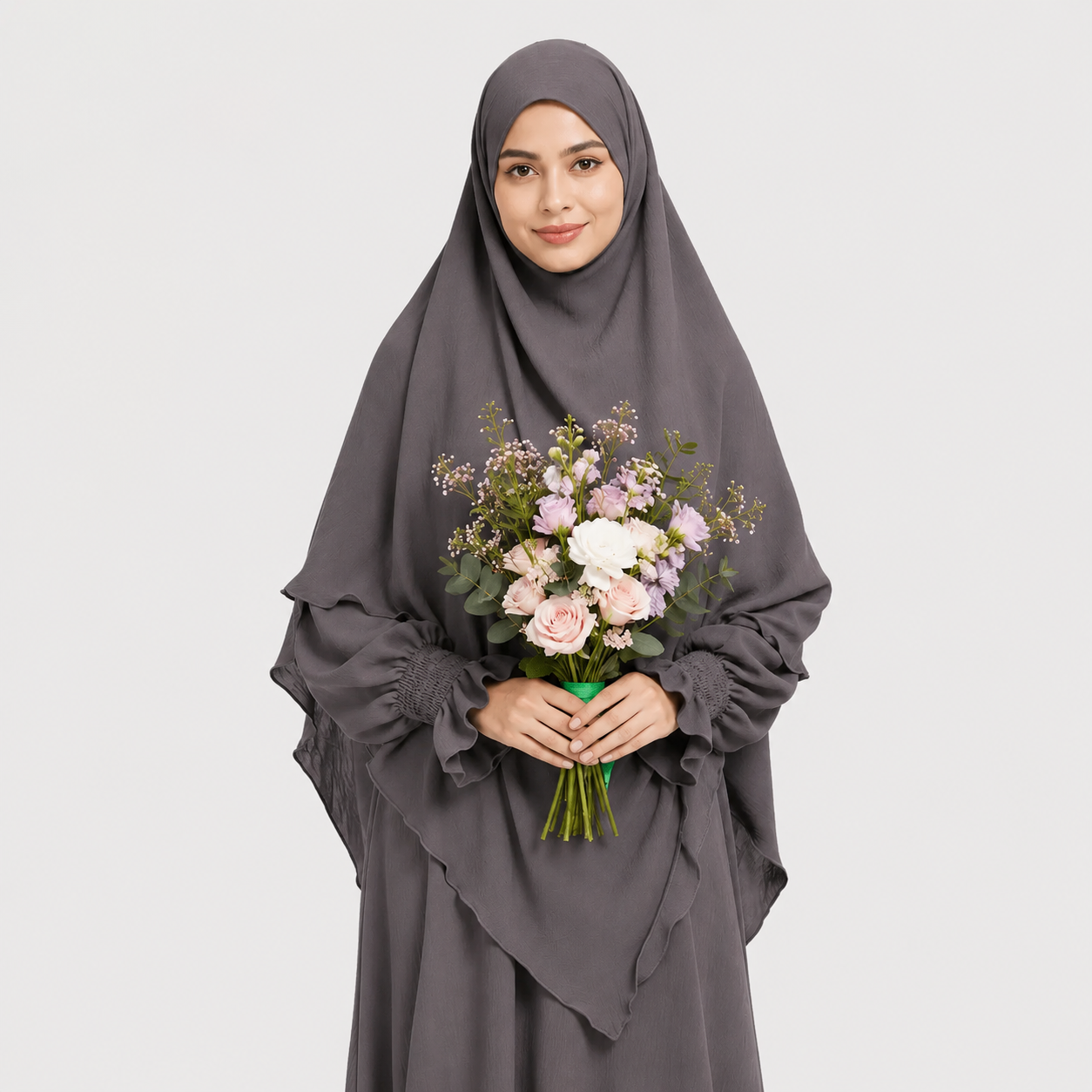 Woman wearing a gray hijab and holding a bouquet of flowers on a white background