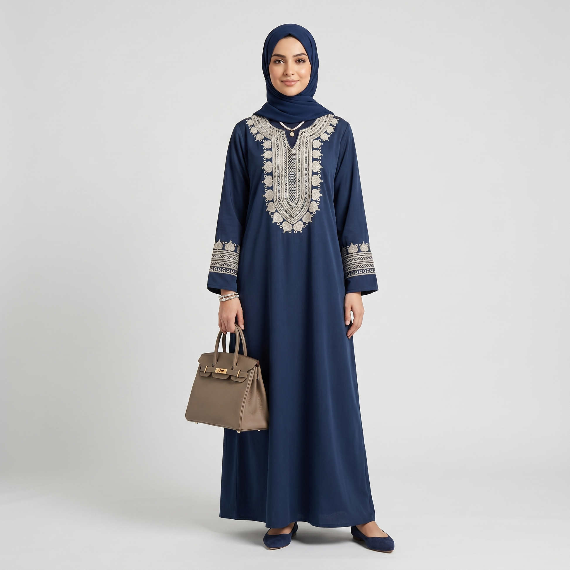 Woman wearing a navy blue dress with beige embroidery on a white background