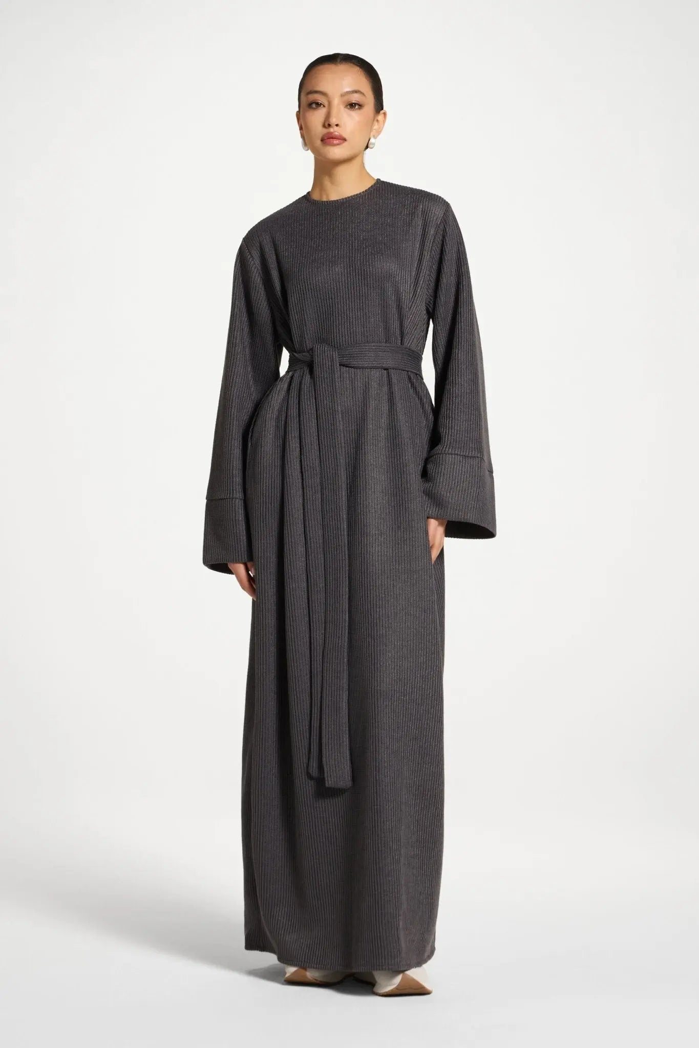 Woman wearing a long dark gray dress on a white background