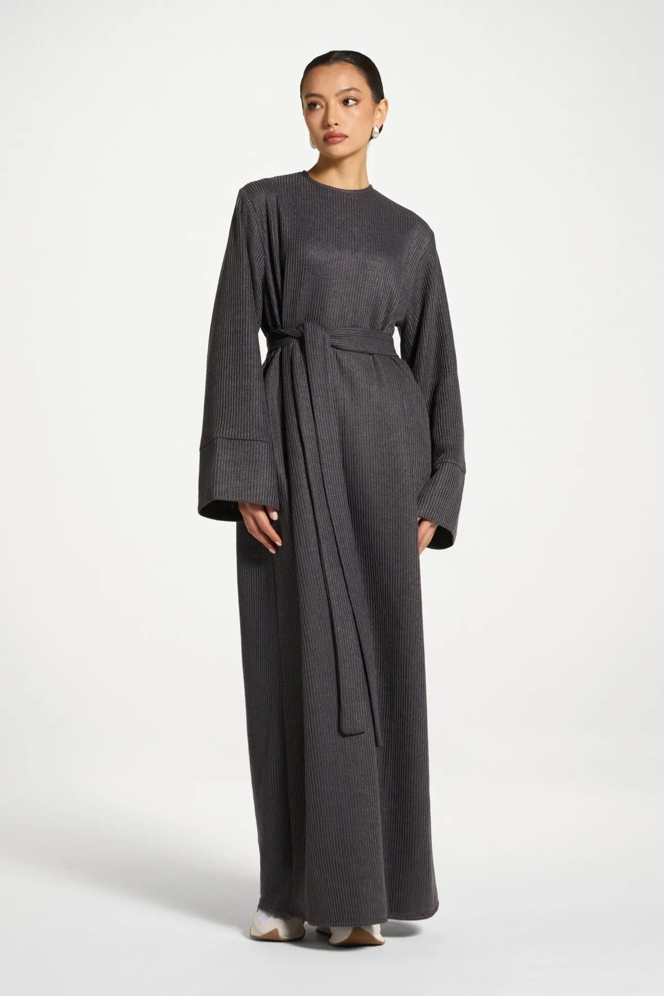 Woman wearing a long dark gray dress on a white background