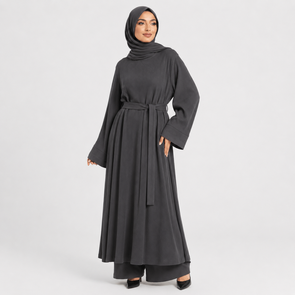 Woman wearing a dark gray abaya with a belt on a light gray background