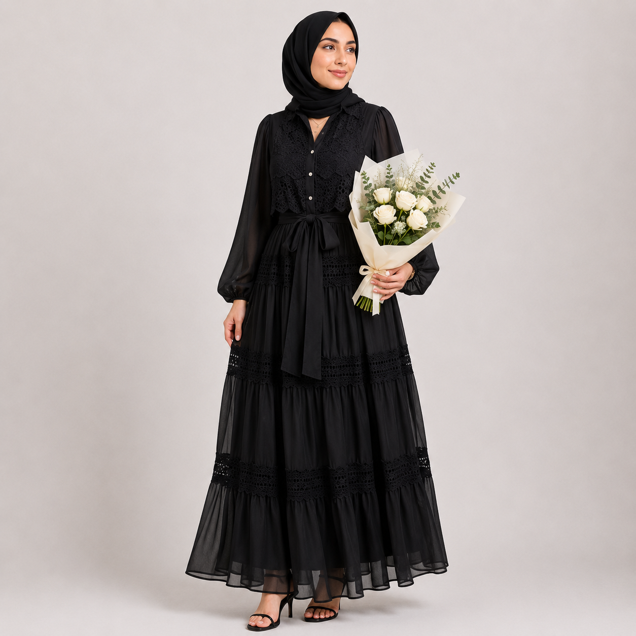 Woman wearing a black dress and hijab holding a bouquet of flowers on a plain background