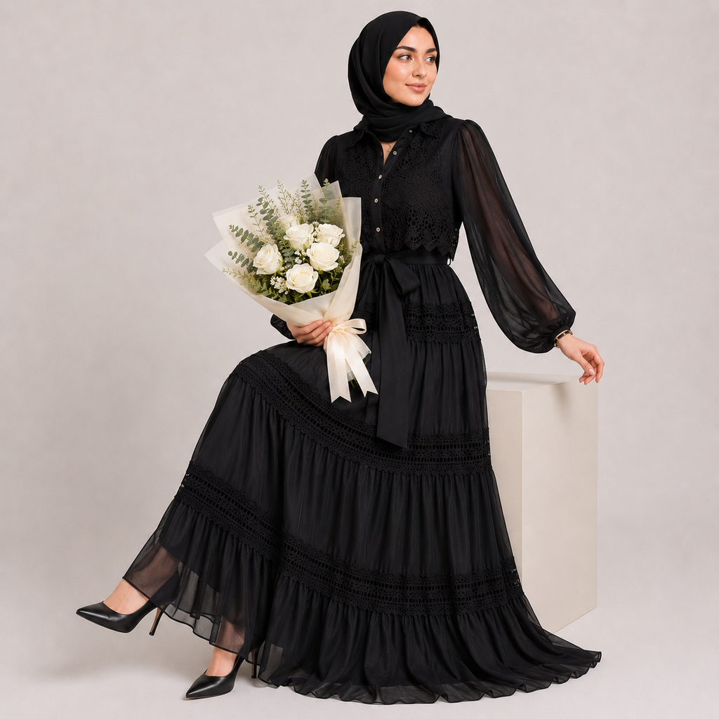 Woman in a black dress holding flowers against a plain background