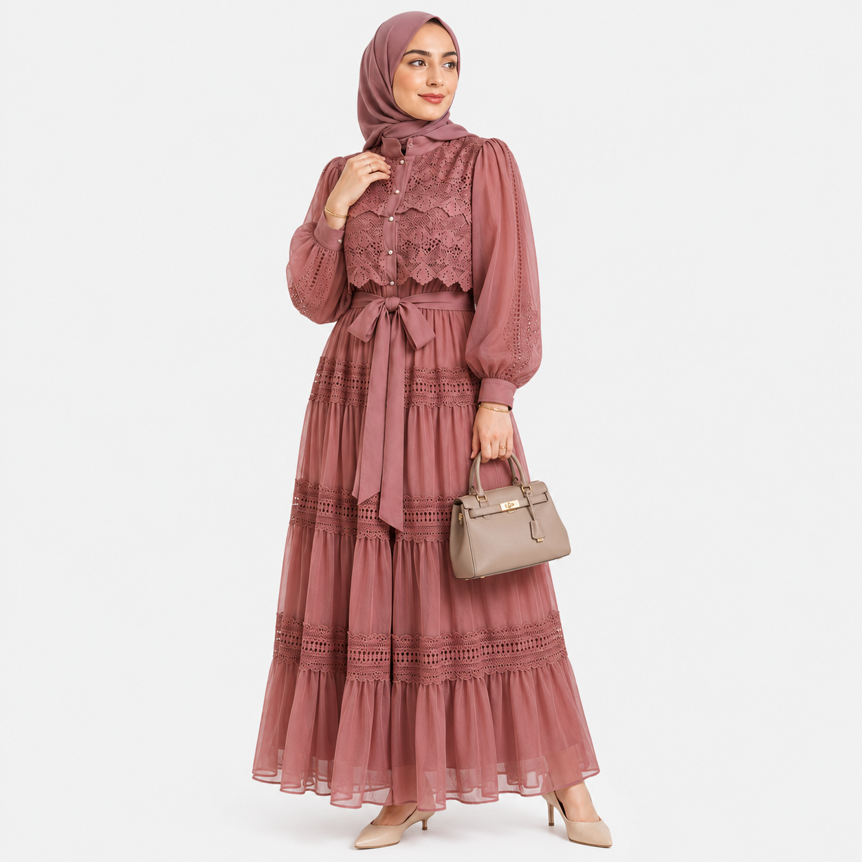 Woman wearing a long pink dress with lace details on a white background