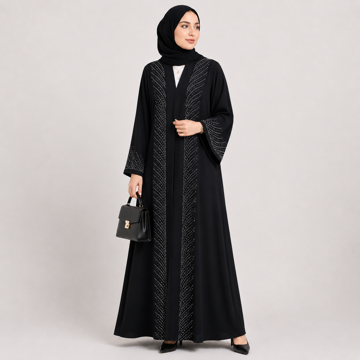 Woman wearing a black abaya with white patterns on a light gray background