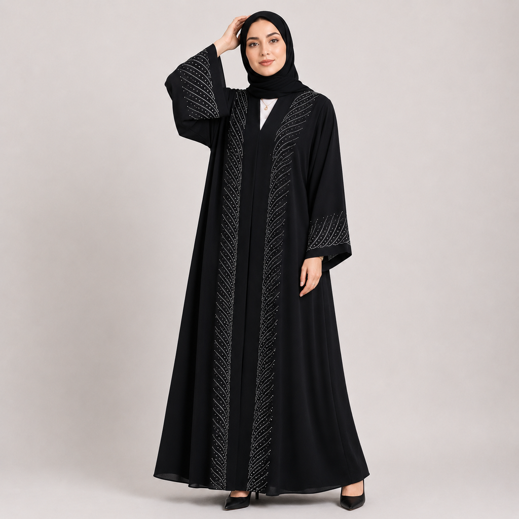 Woman wearing a black abaya with intricate designs on a plain background