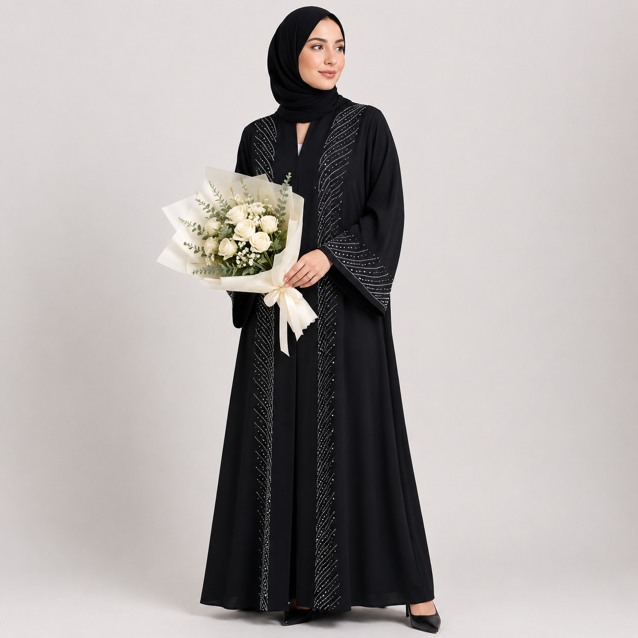 Woman in a black abaya holding flowers on a white background