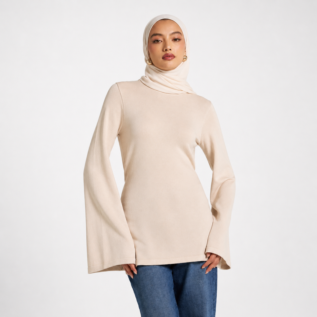 Woman wearing a beige turtleneck sweater and blue jeans on a white background