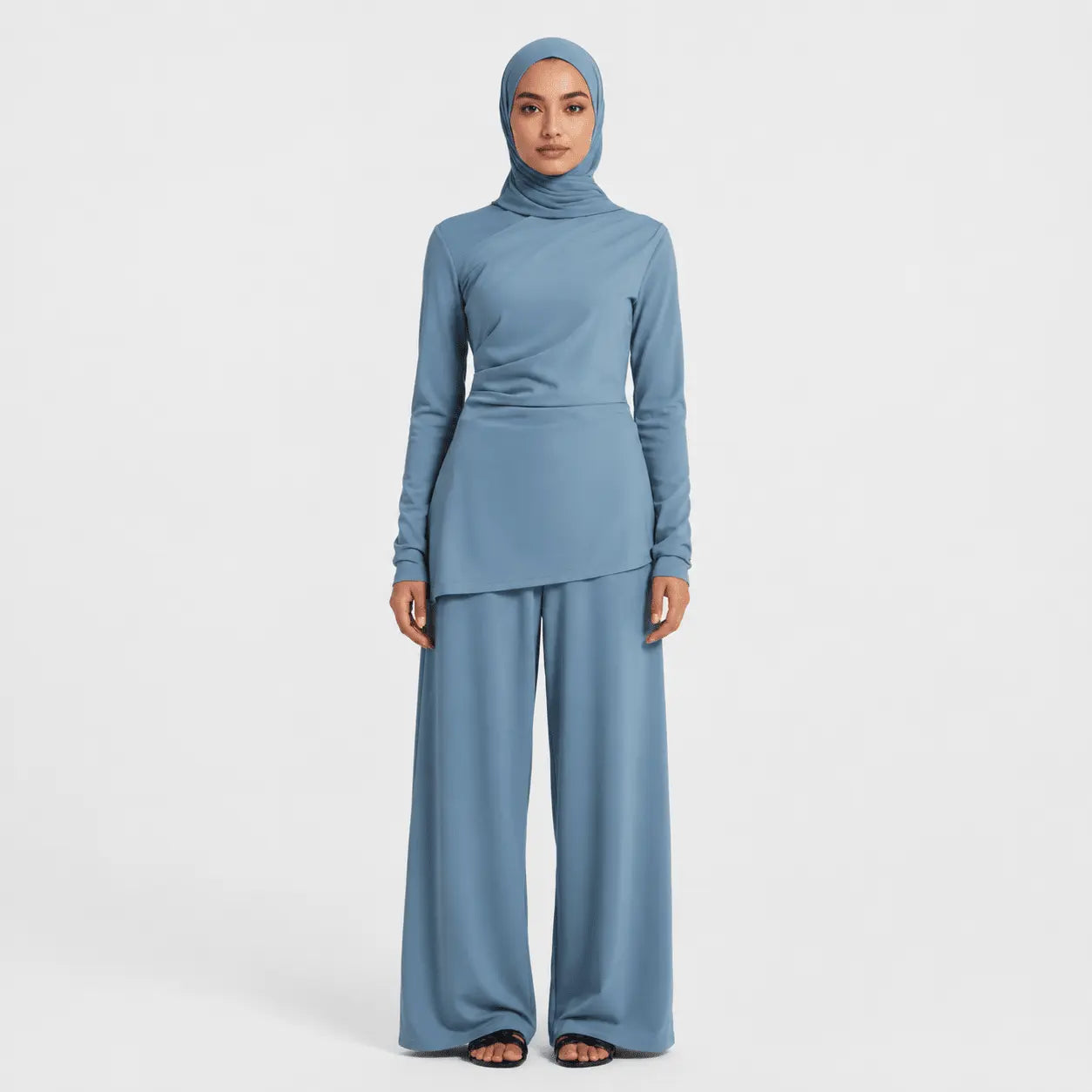 Woman wearing a blue outfit with a hijab on a white background