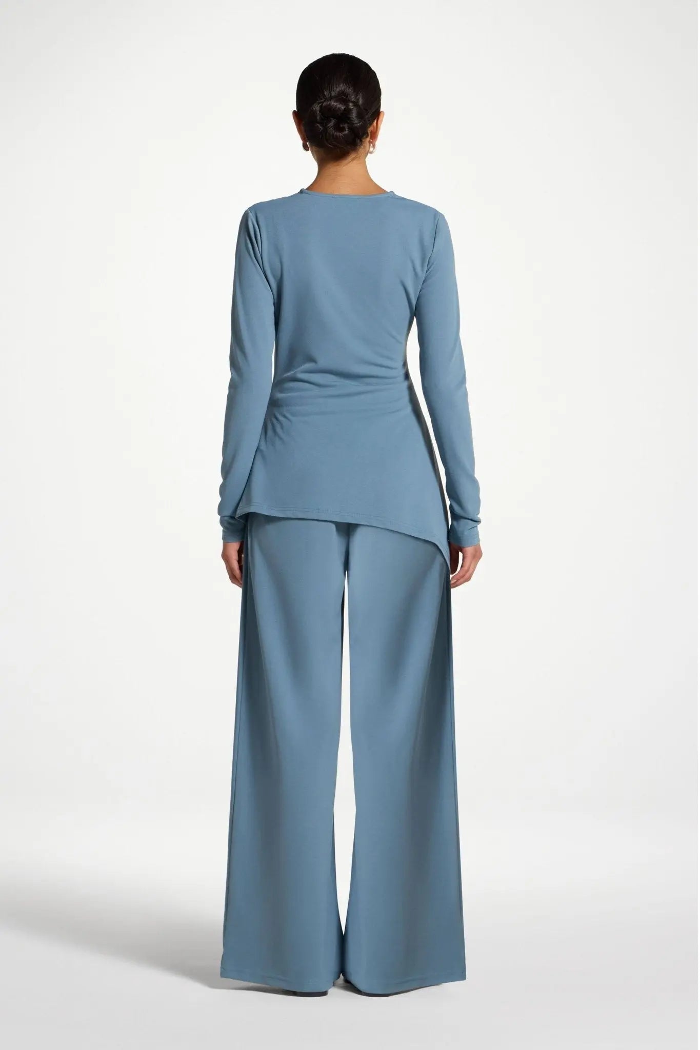 Person wearing a light blue outfit with wide-leg pants on a white background