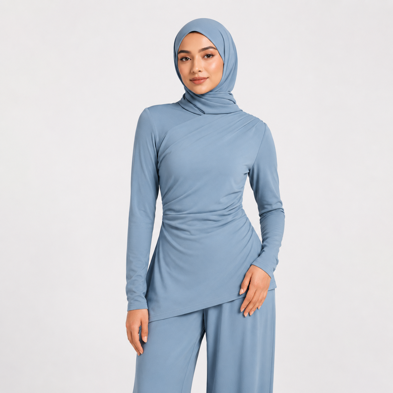 Woman wearing a light blue outfit with a matching hijab on a white background