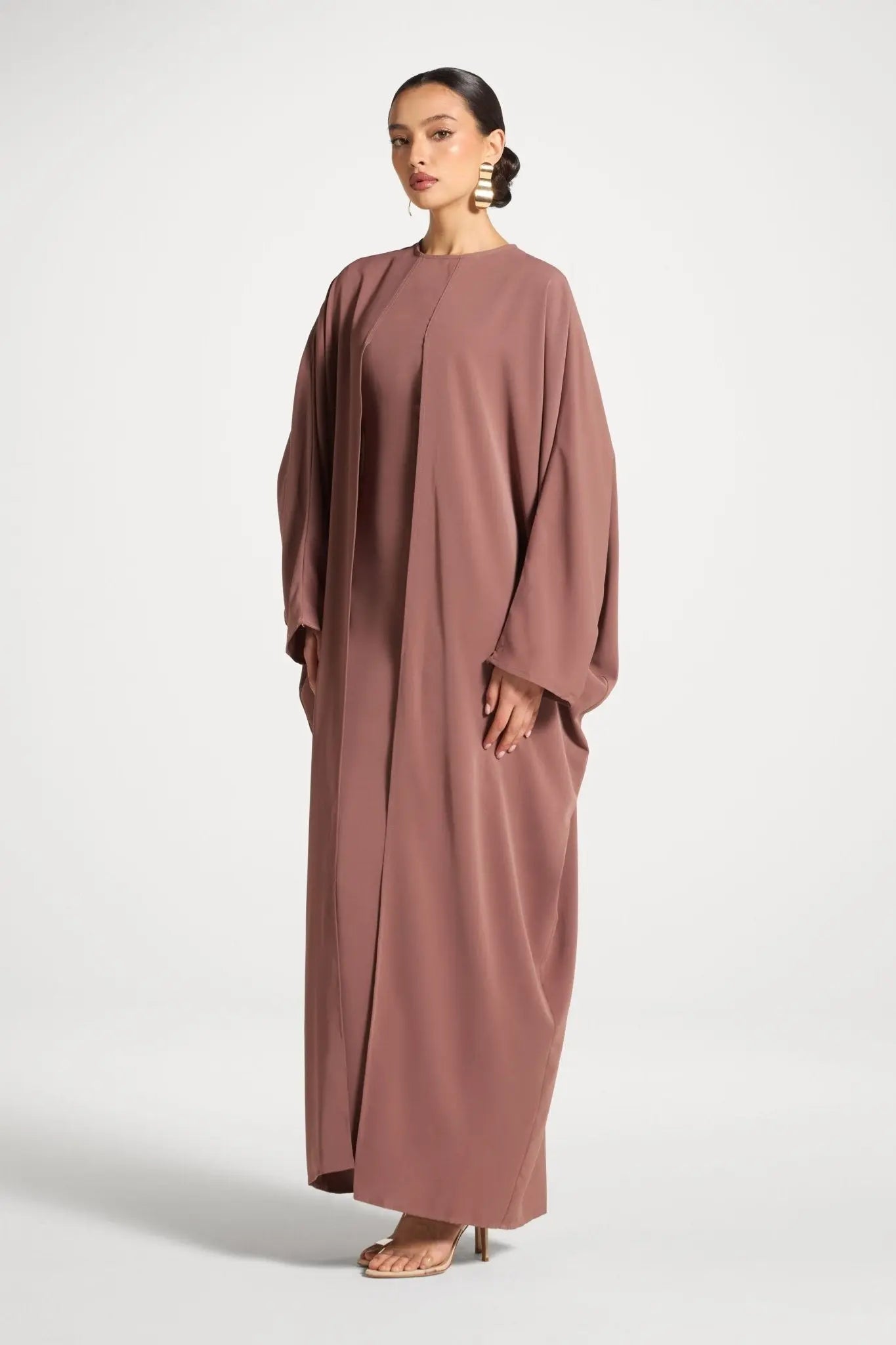 Woman wearing a long, brown dress on a white background