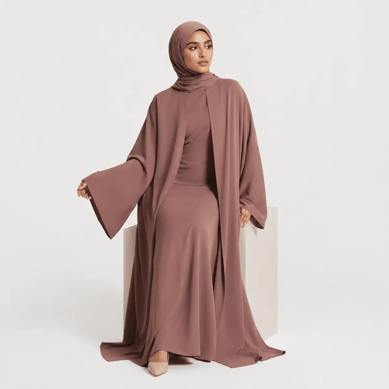 Woman wearing a brown abaya and hijab on a white background