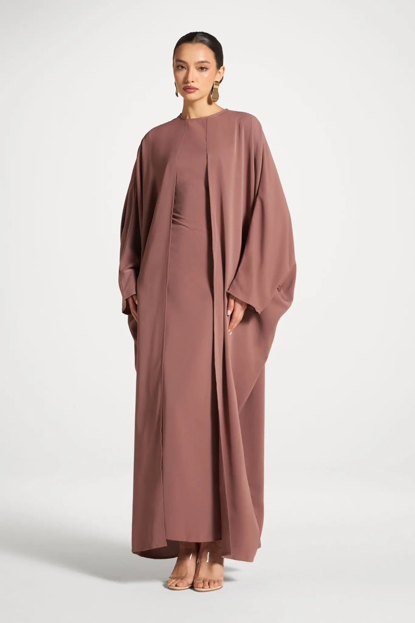 Woman wearing a long, flowing brown dress on a white background