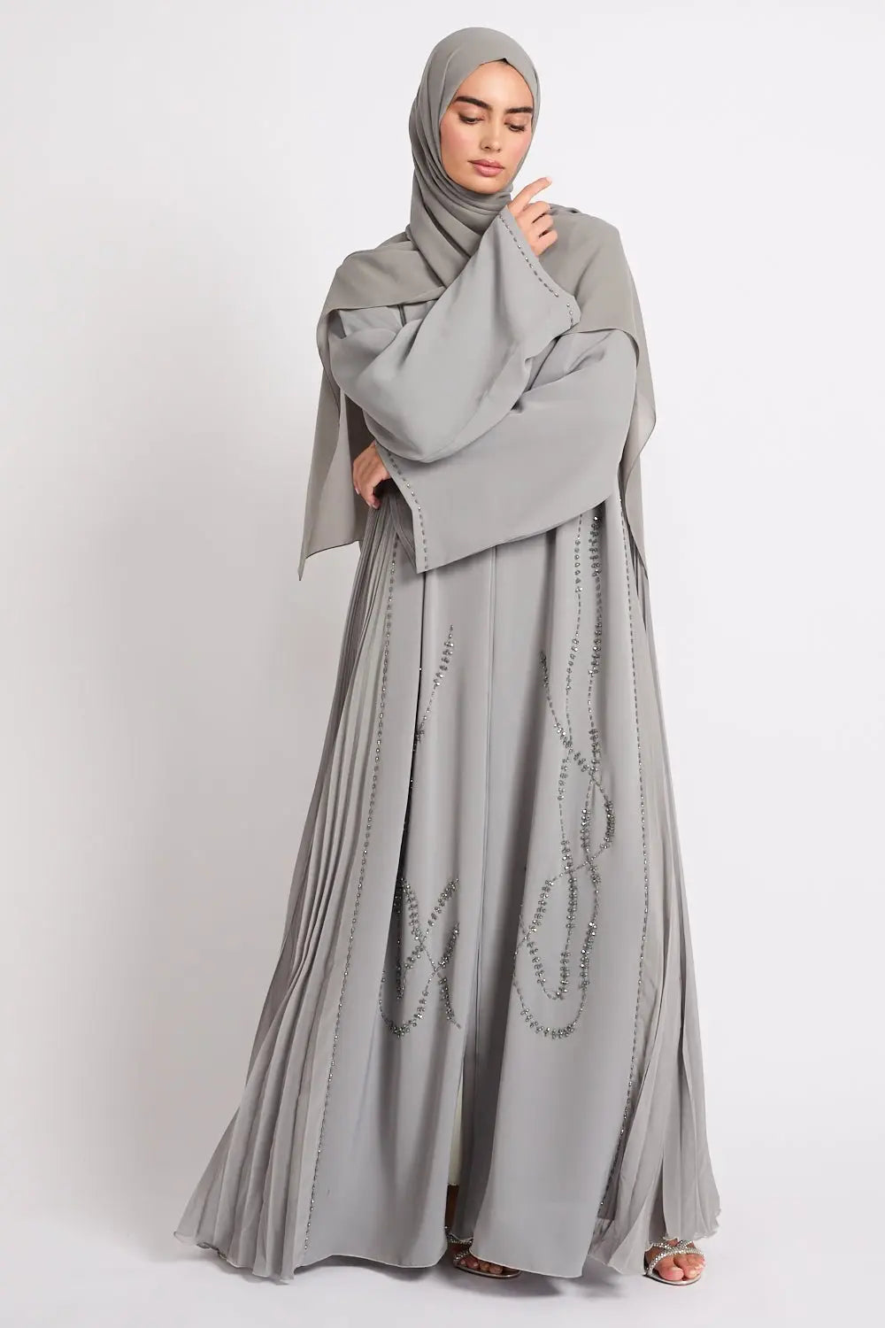 Woman wearing a gray abaya with a matching hijab on a white background
