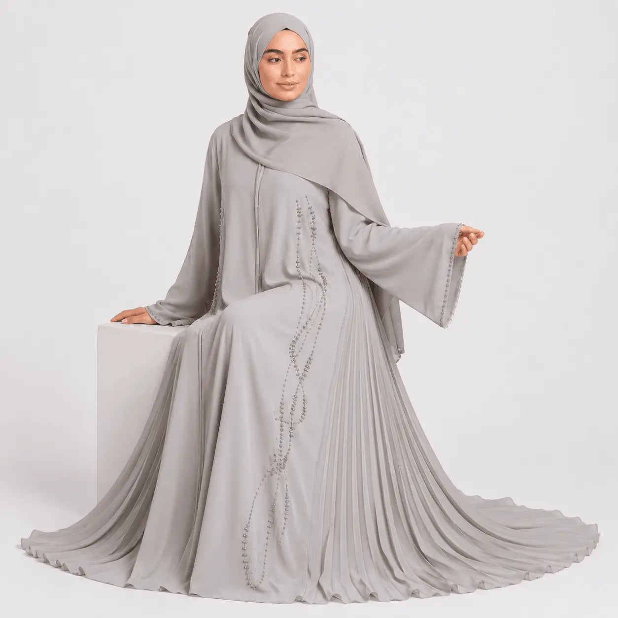 Woman wearing a gray abaya with a matching hijab on a white background
