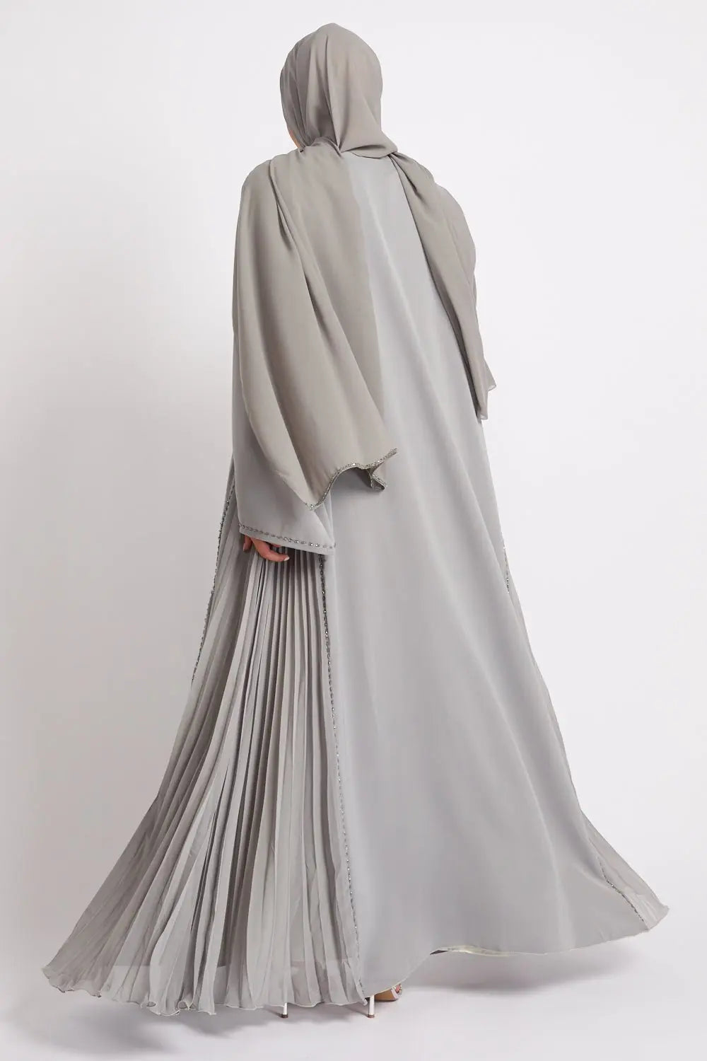 Person wearing a long, light gray dress with a hood on a white background