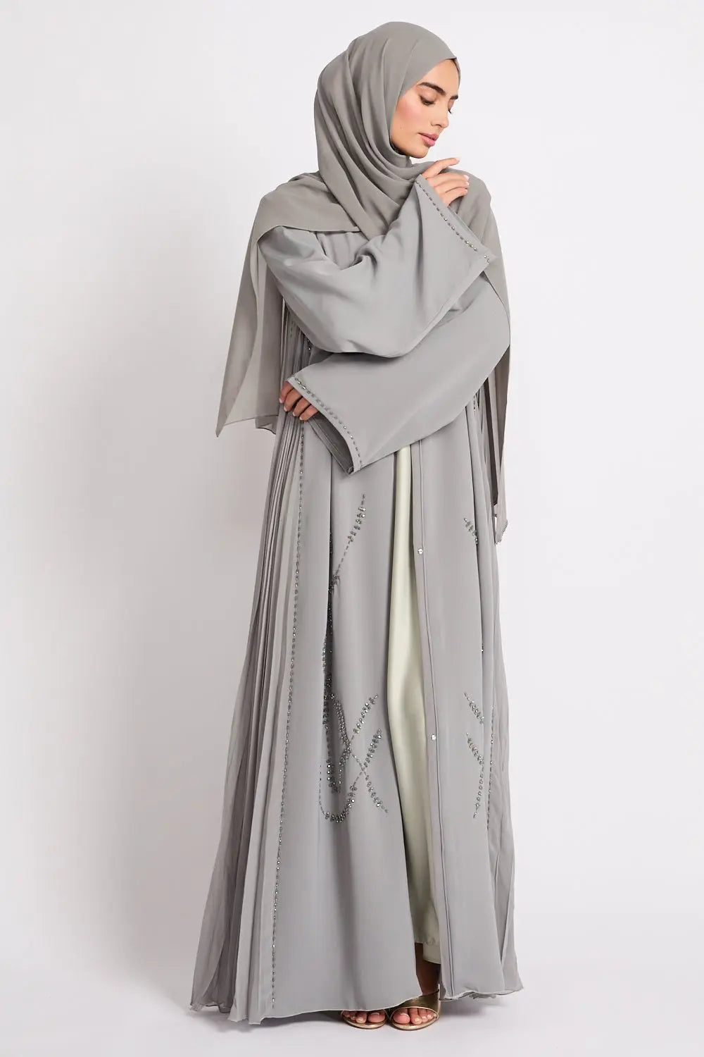 Woman wearing a gray abaya and hijab on a white background
