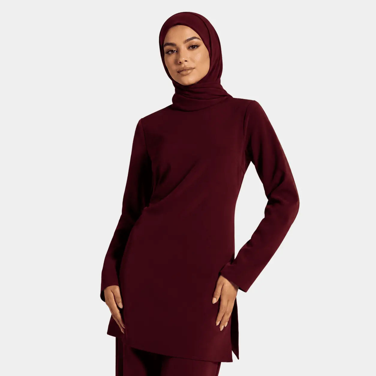 Person wearing a burgundy outfit with a matching hijab on a white background