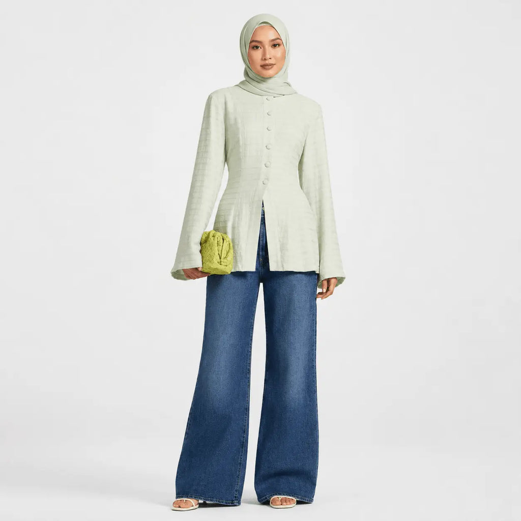 Woman wearing a light green cardigan and blue jeans on a white background