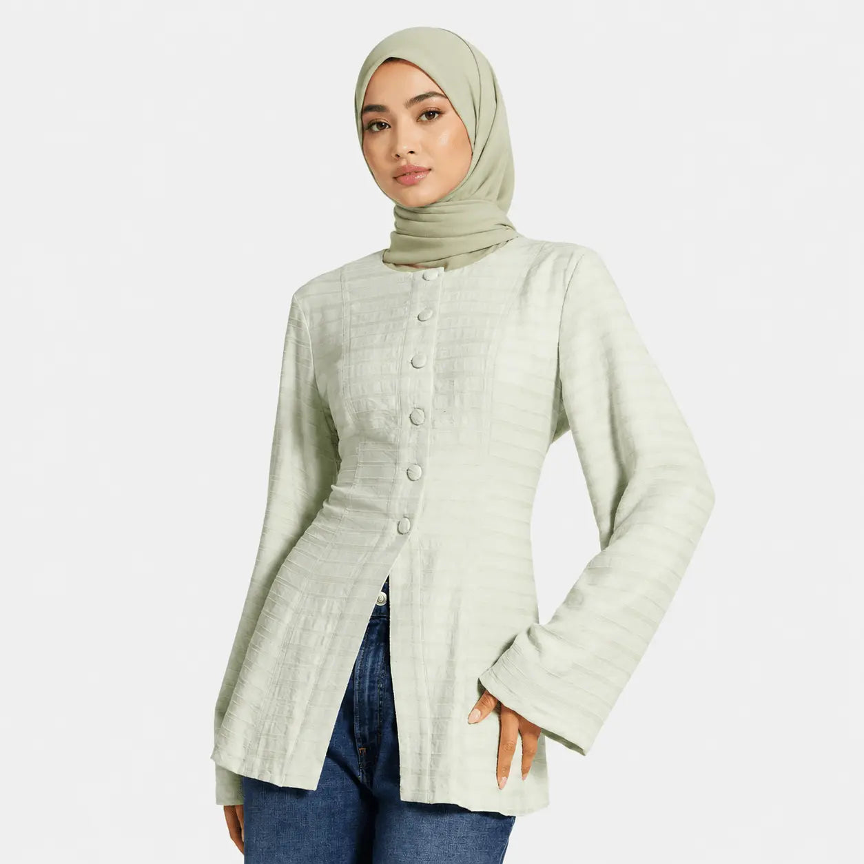 Woman wearing a light green jacket and hijab on a white background