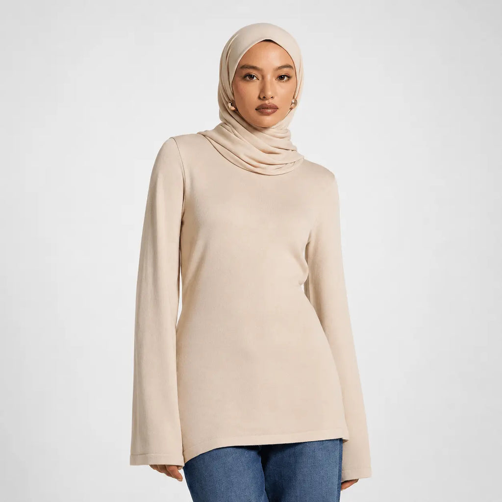 Woman wearing a beige hijab and long-sleeve top on a white background