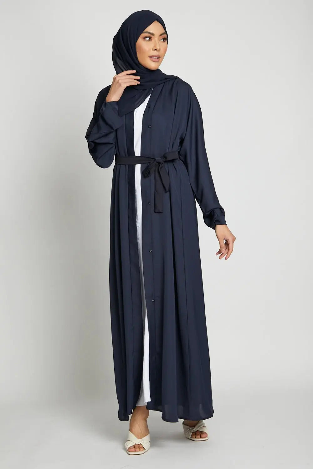 Woman wearing a long navy blue dress with a hood on a white background