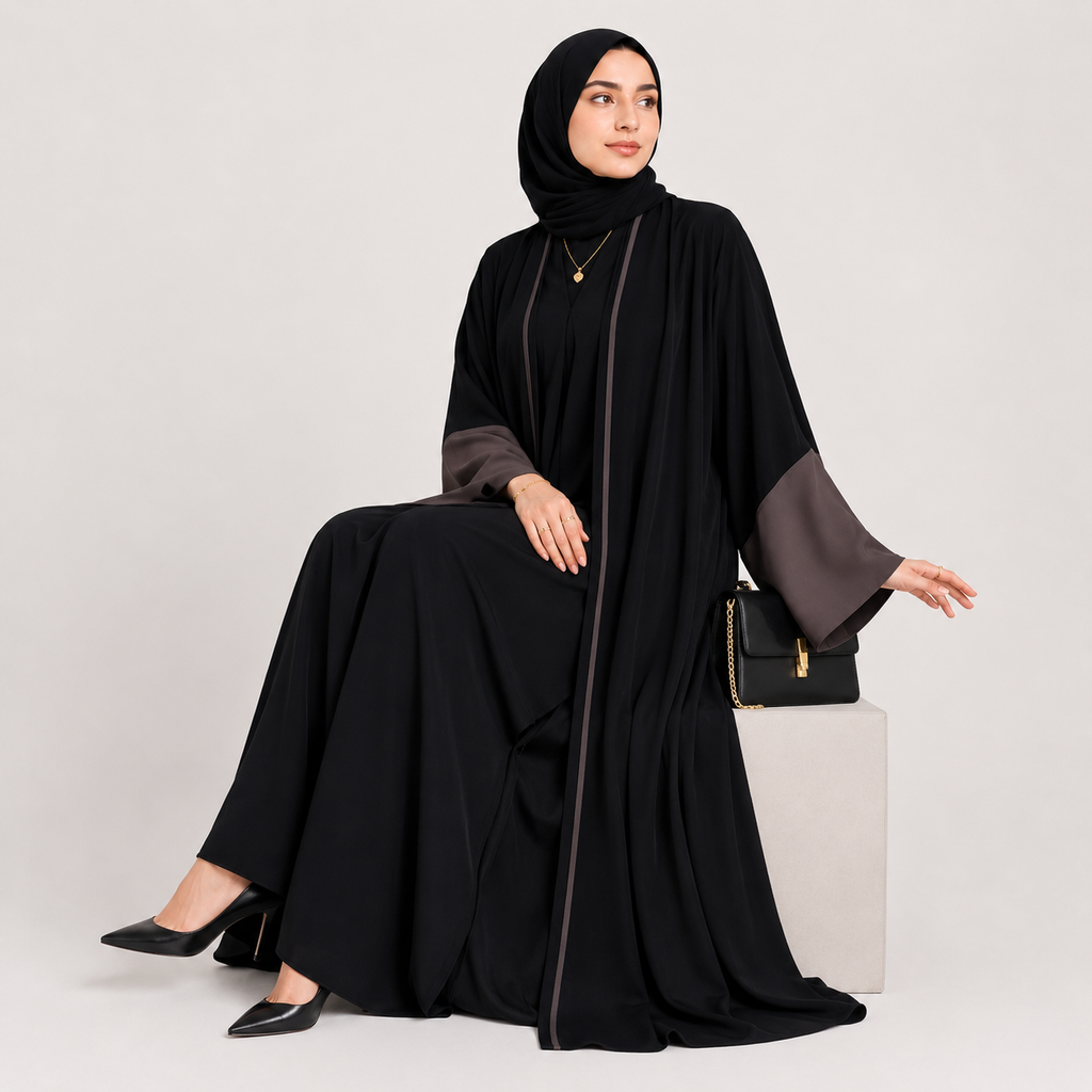 Woman wearing a black abaya with gray sleeves on a white background