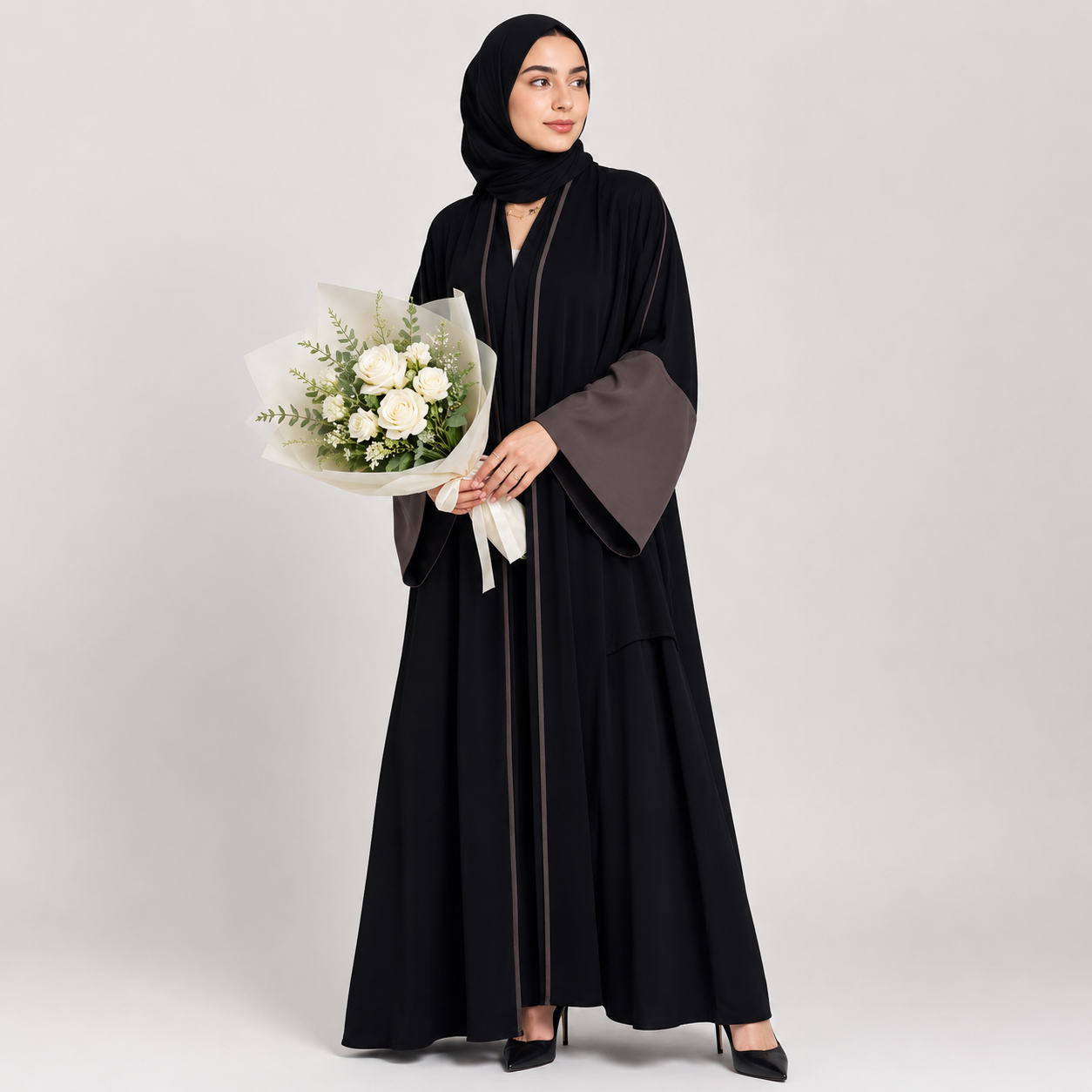 Woman in a black abaya holding a bouquet of flowers on a white background