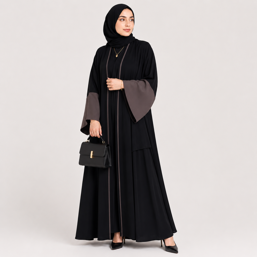 Woman wearing a black abaya with gray sleeves on a light gray background