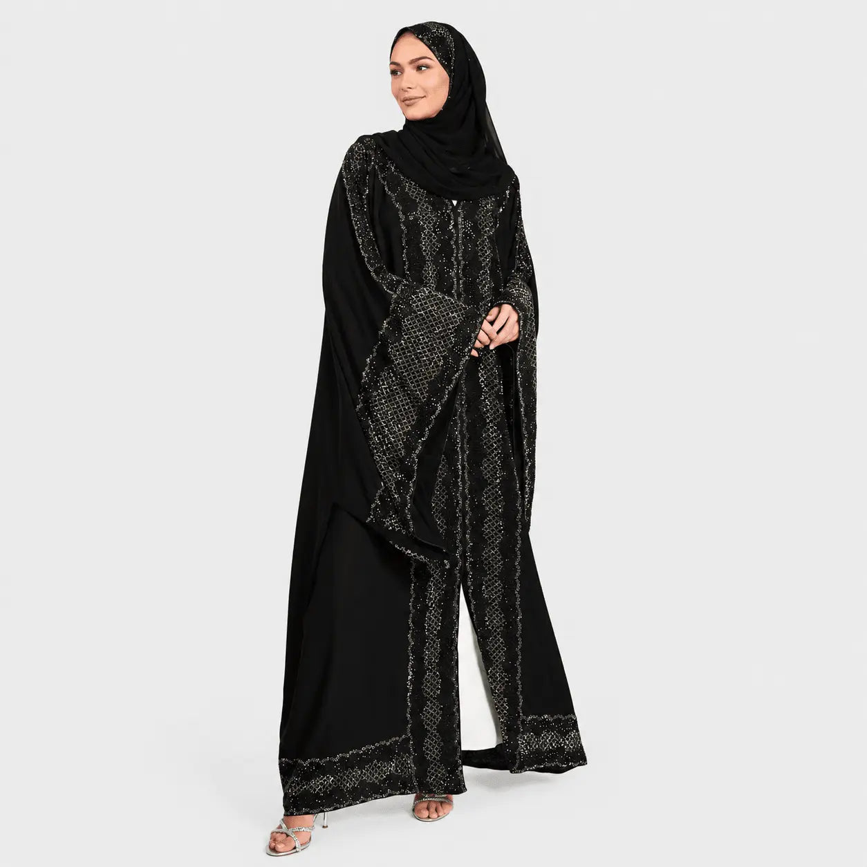 Woman wearing a black abaya with intricate patterns on a white background