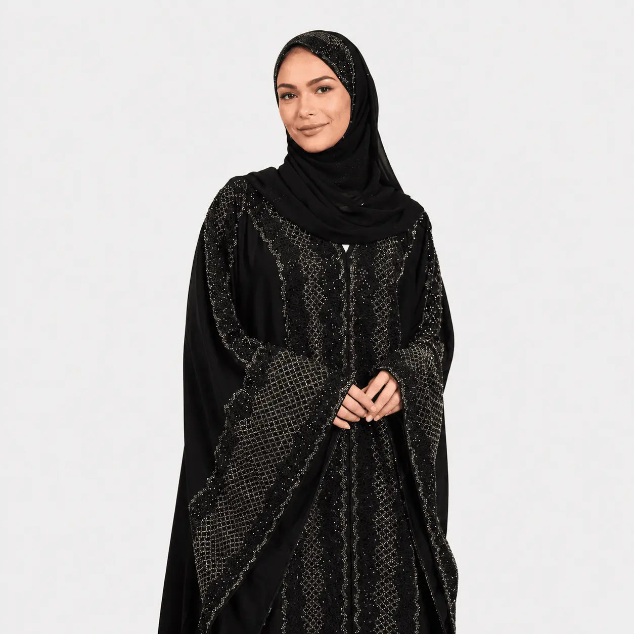 Woman wearing a black abaya with intricate patterns on a white background