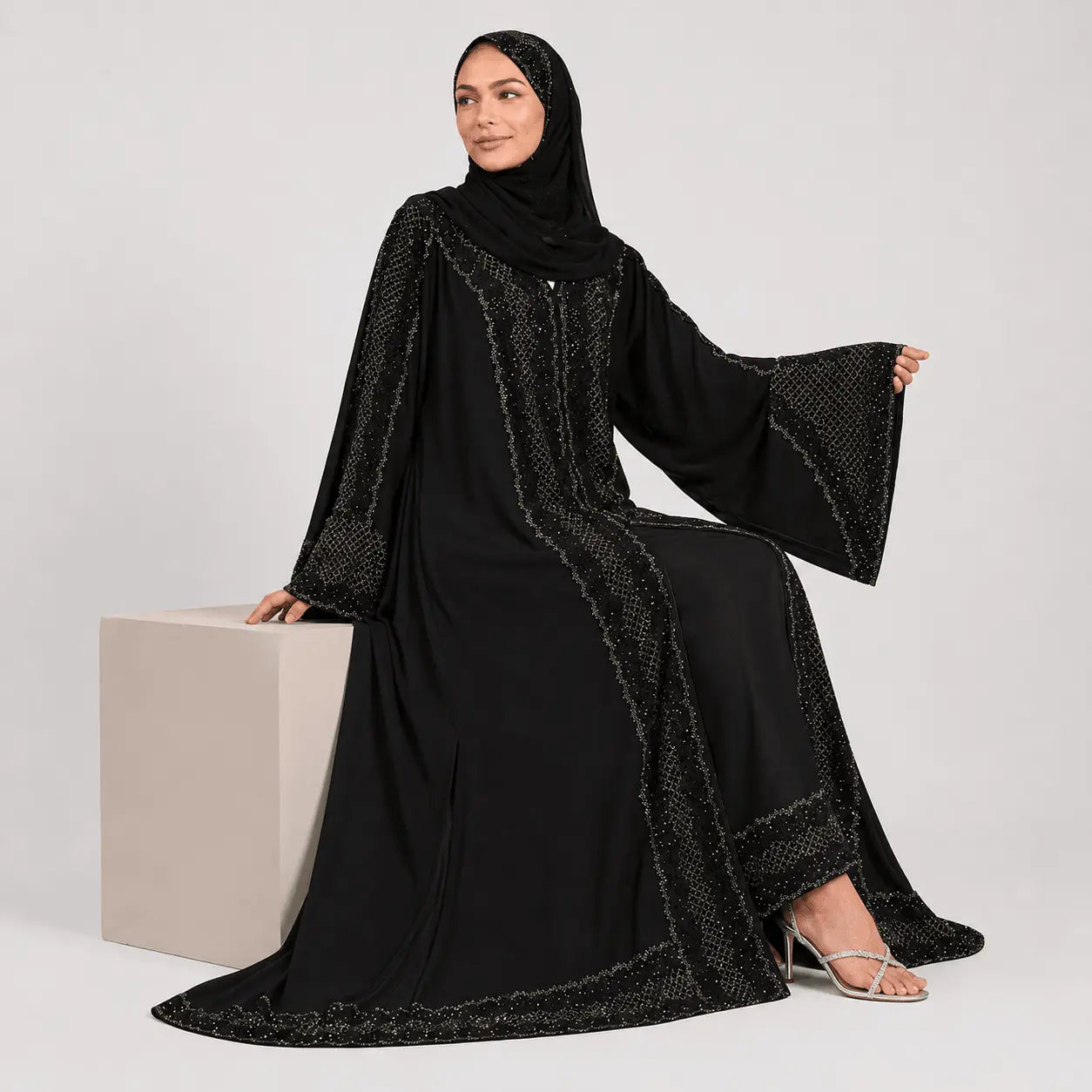 Woman wearing a black abaya with intricate designs on a white background