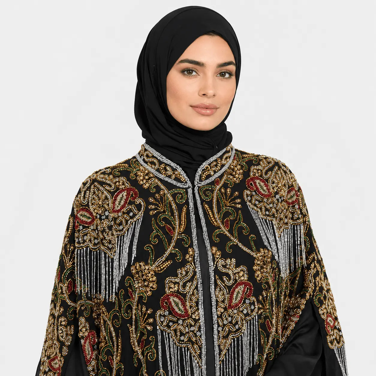 Woman wearing a black hijab and an intricately designed jacket with gold and red patterns on a white background