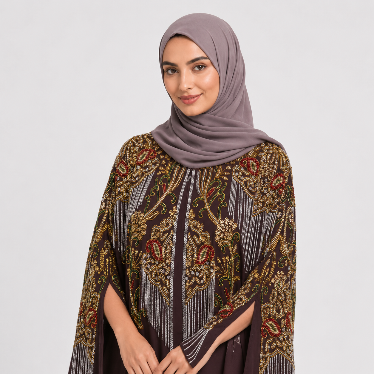 Woman wearing a dark brown dress with intricate patterns and a matching hijab on a white background