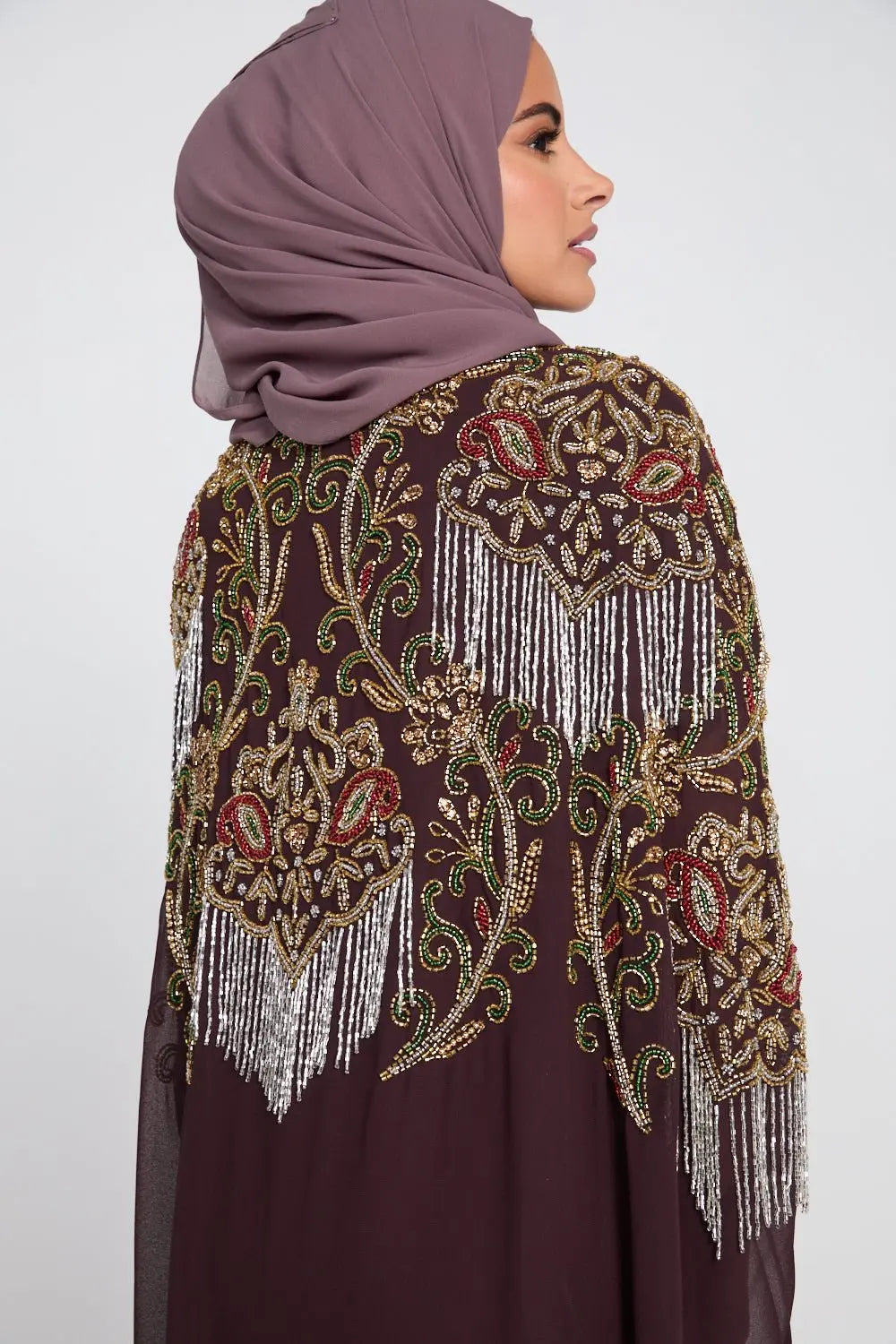 Decorative shawl with intricate patterns and fringes on a plain background