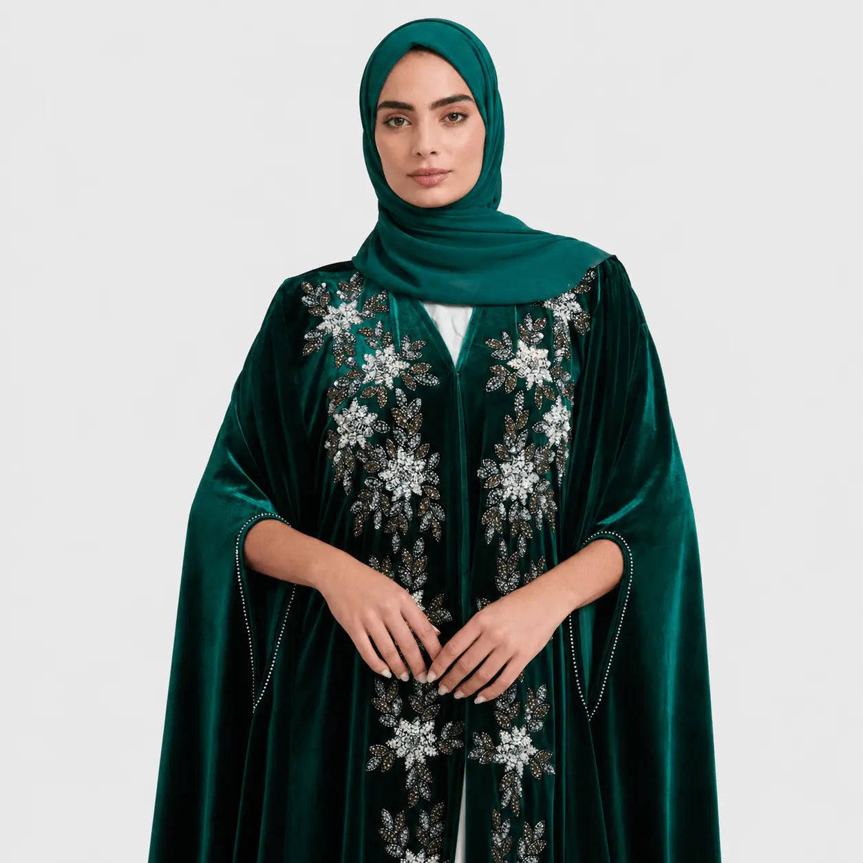 Woman wearing a green embroidered abaya on a white background