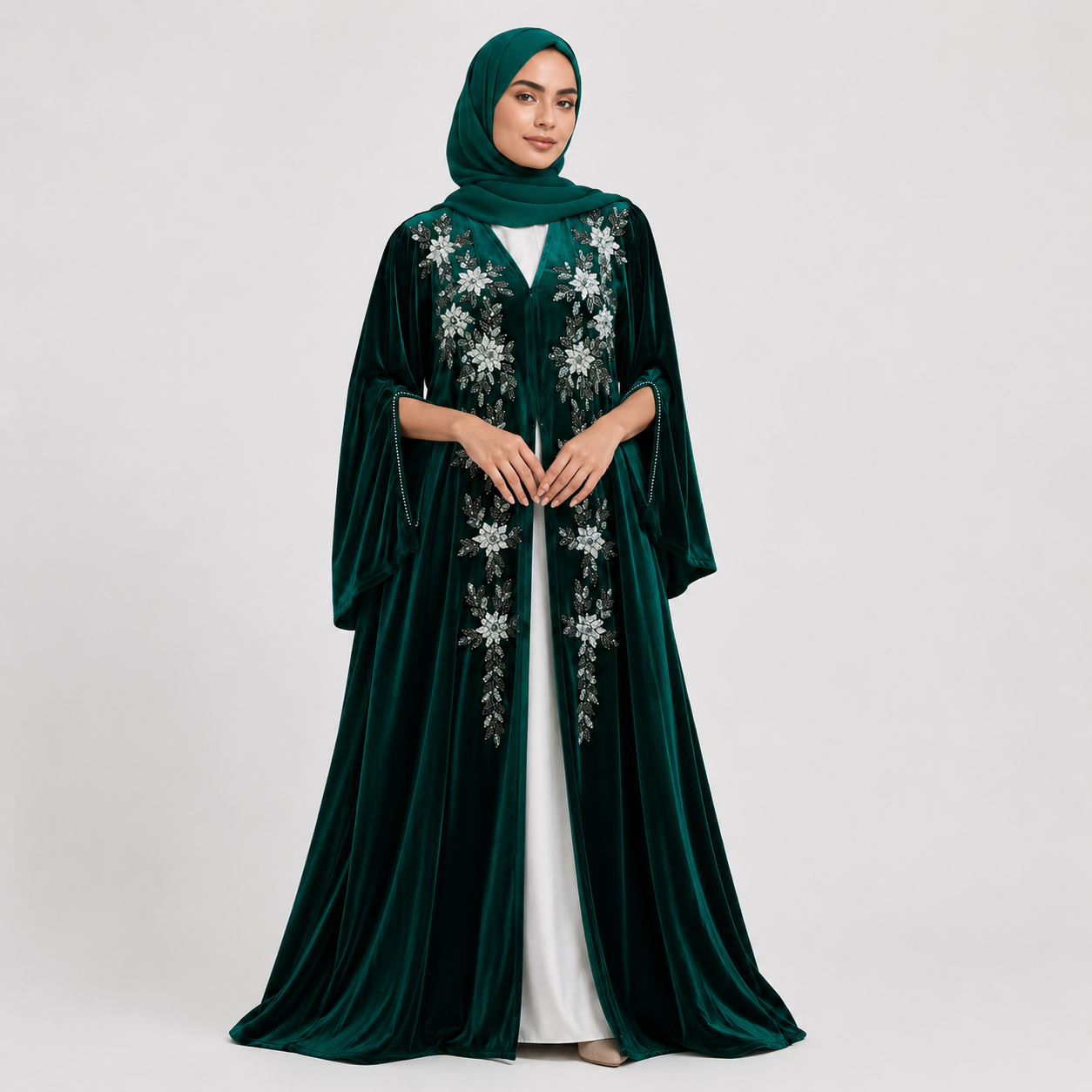 Woman wearing a dark green abaya with floral embroidery on a white background