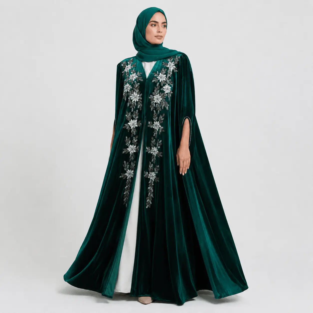 Woman wearing a green embroidered dress with a hood on a white background