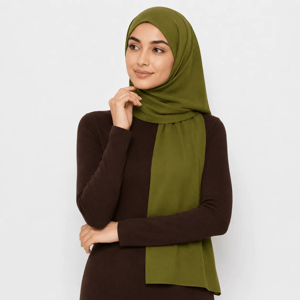 Woman wearing a green hijab and brown top against a white background