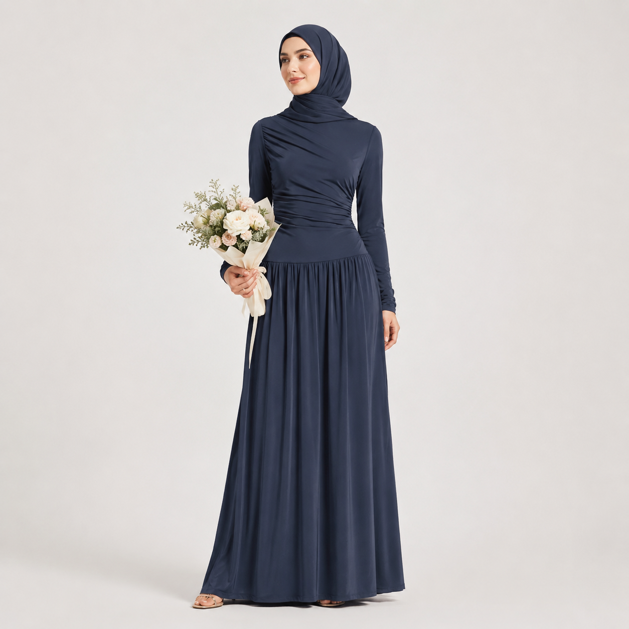 Woman wearing a navy blue hijab and long-sleeve dress holding flowers on a light gray background