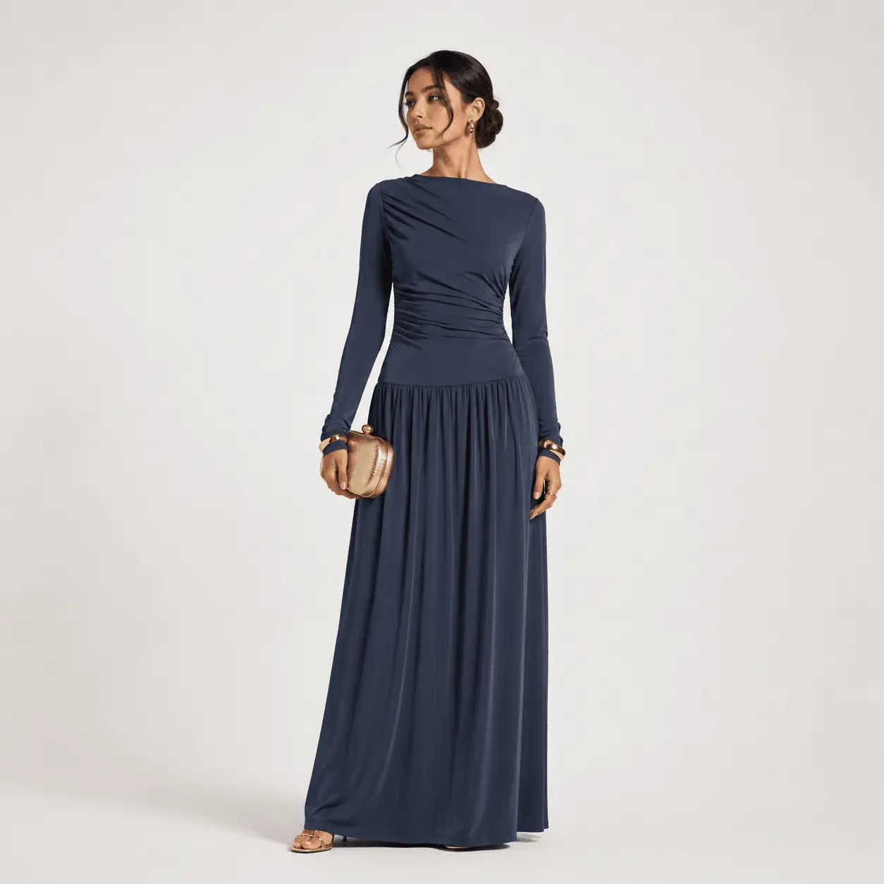 Navy blue long-sleeve maxi dress with ruched bodice and flowy skirt, styled with gold clutch and sandals