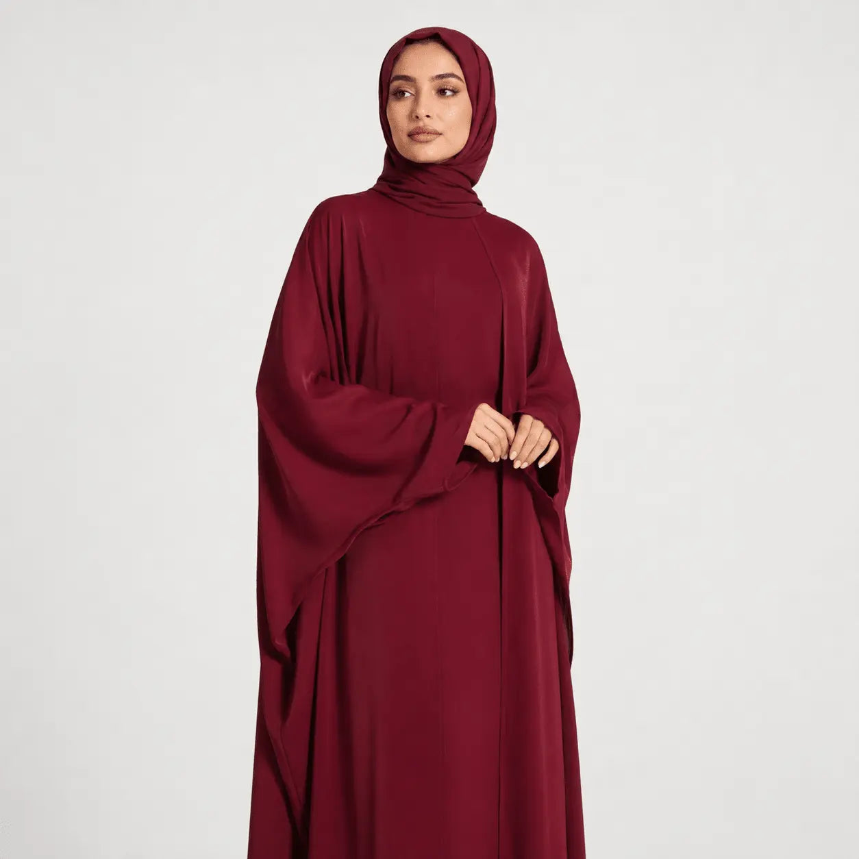 Woman wearing a burgundy abaya on a white background