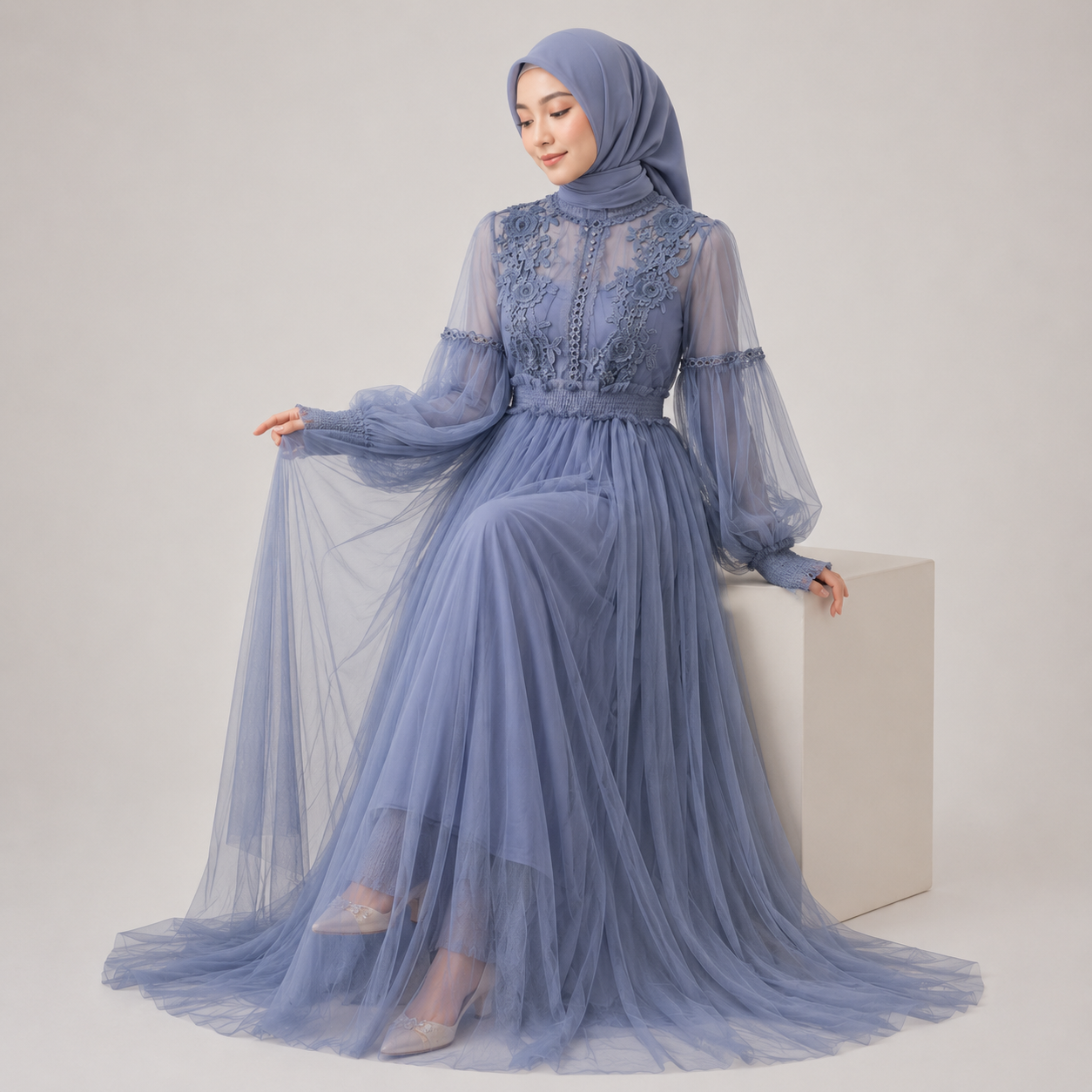 Woman wearing a long, light blue dress with lace details on a white background