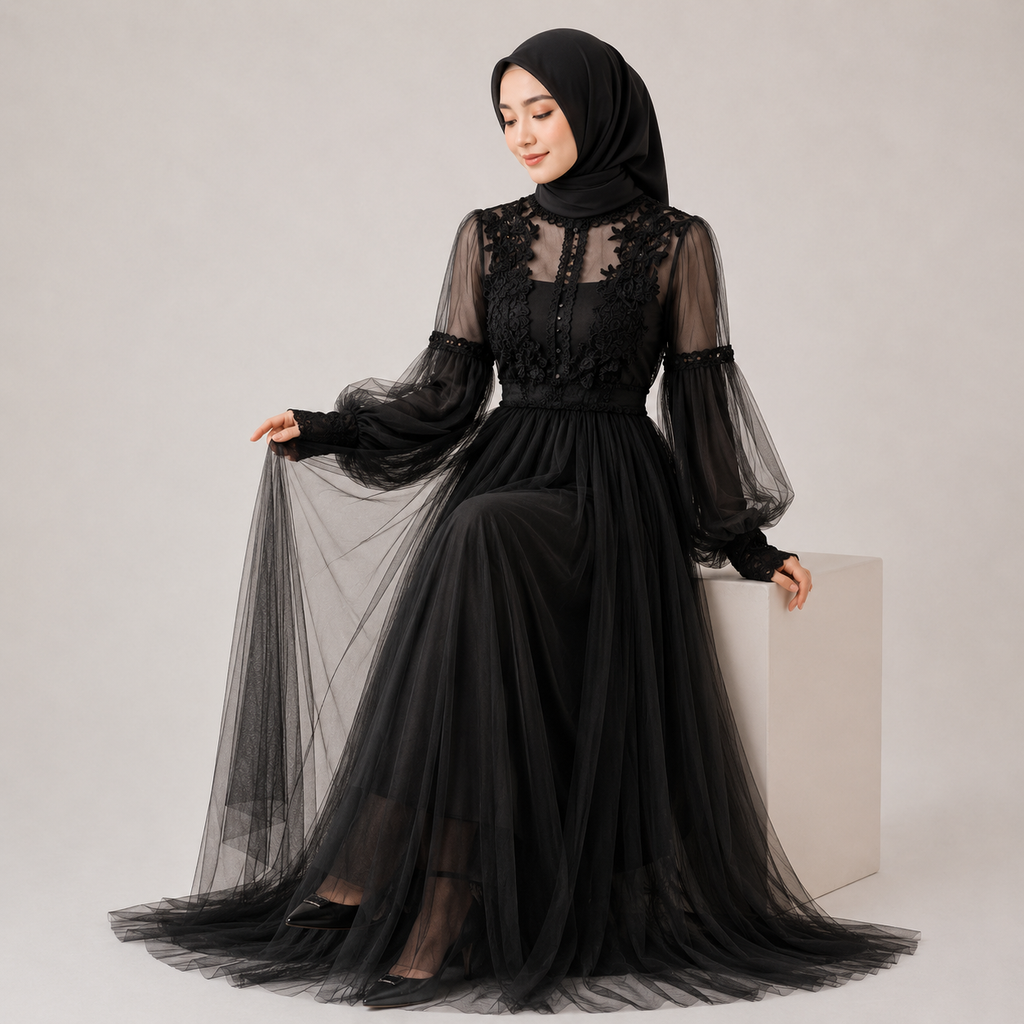 Woman wearing a black dress with sheer sleeves against a plain background